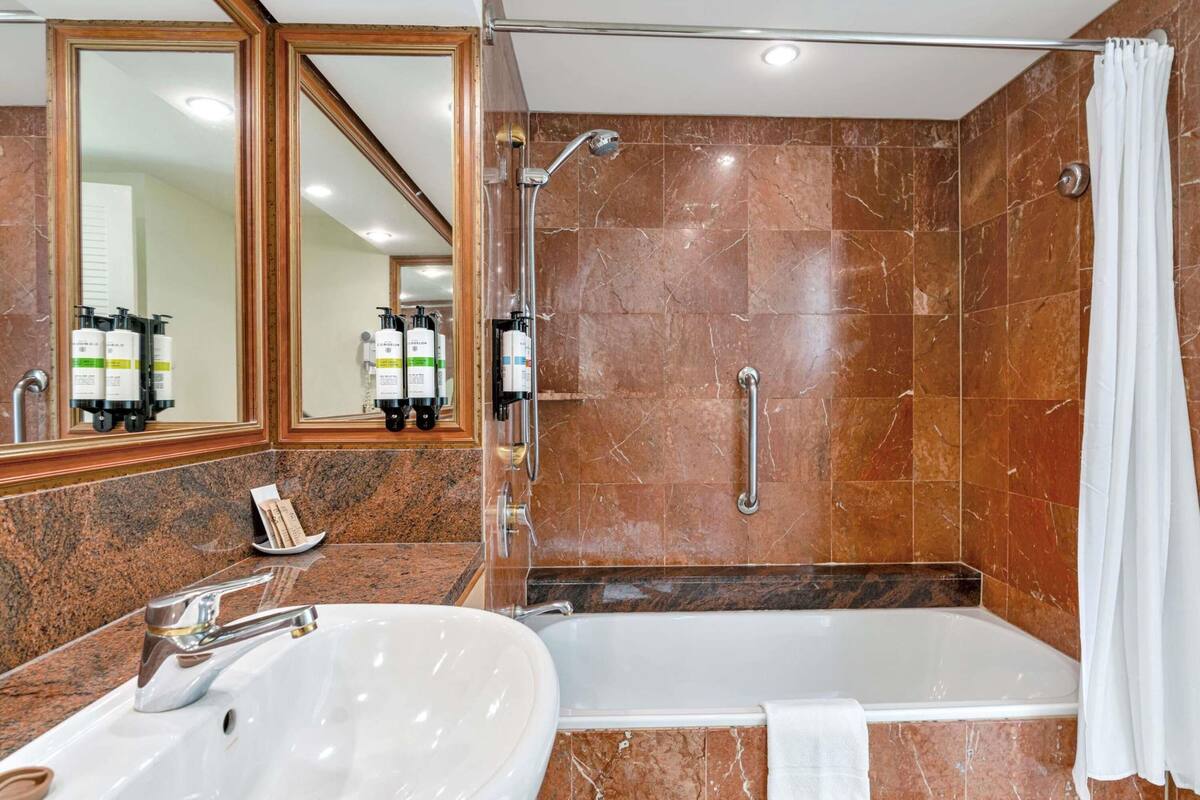 Une salle de bain équipée d’un lavabo, d’un miroir, d’une douche et d’une baignoire.