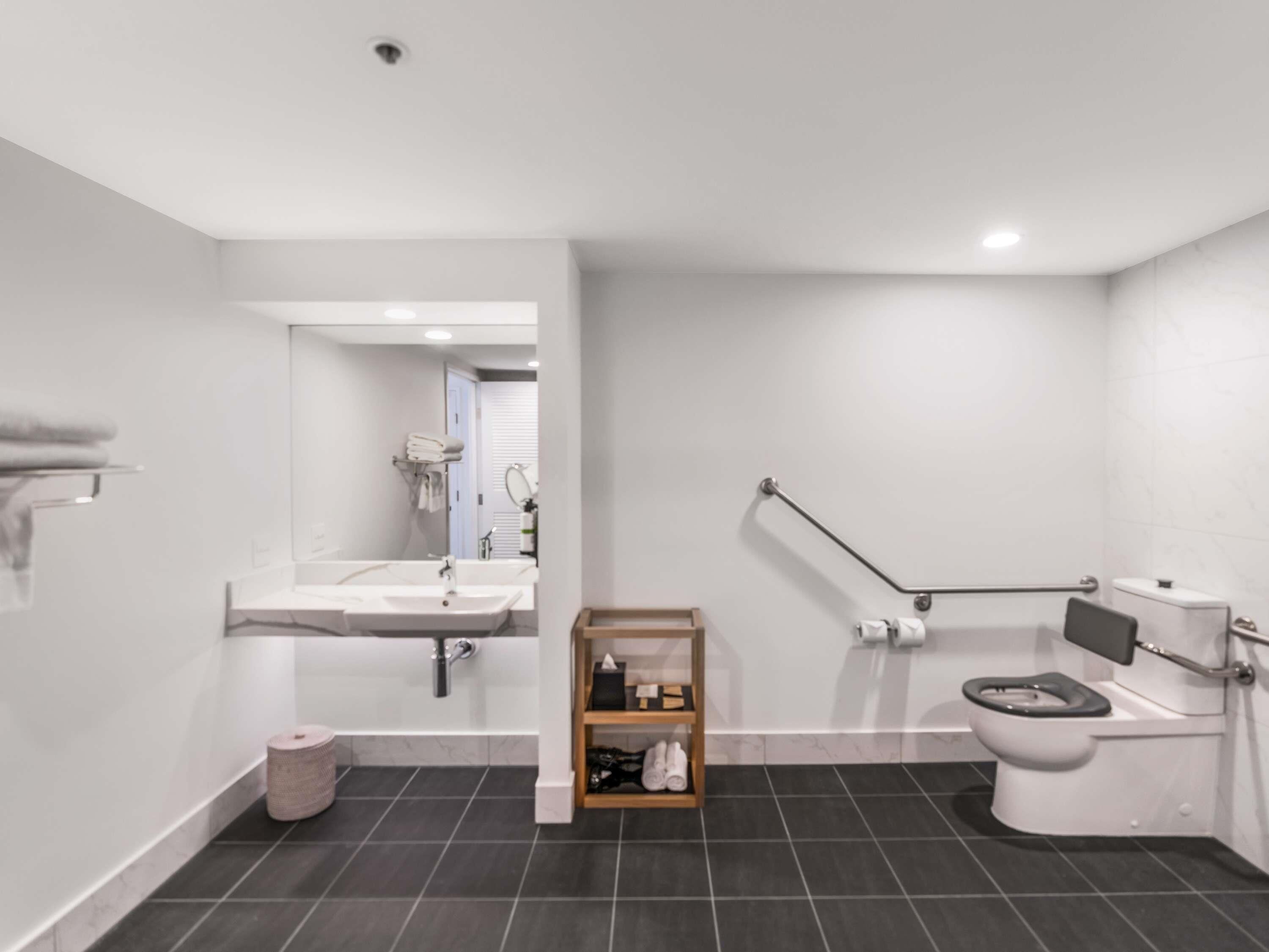 A modern bathroom with a white sink, a toilet, and a shower area.