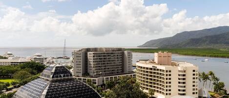 Hotel com grande estrutura de vidro, vários edifícios, piscina e vista para o mar.