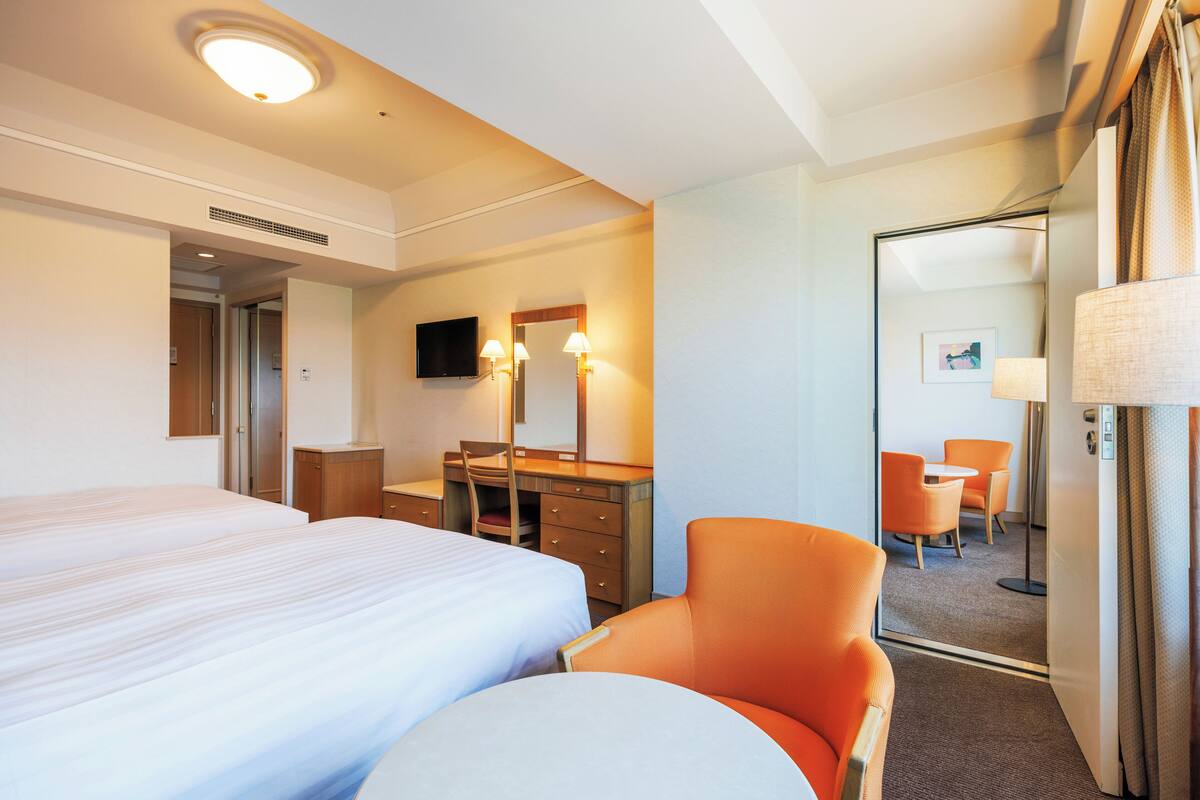 Une chambre d’hôtel avec un grand lit, un bureau avec une chaise, une télévision et un miroir.