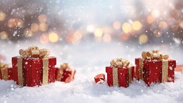 A snowy scene with multiple red gift boxes adorned with golden ribbons.
