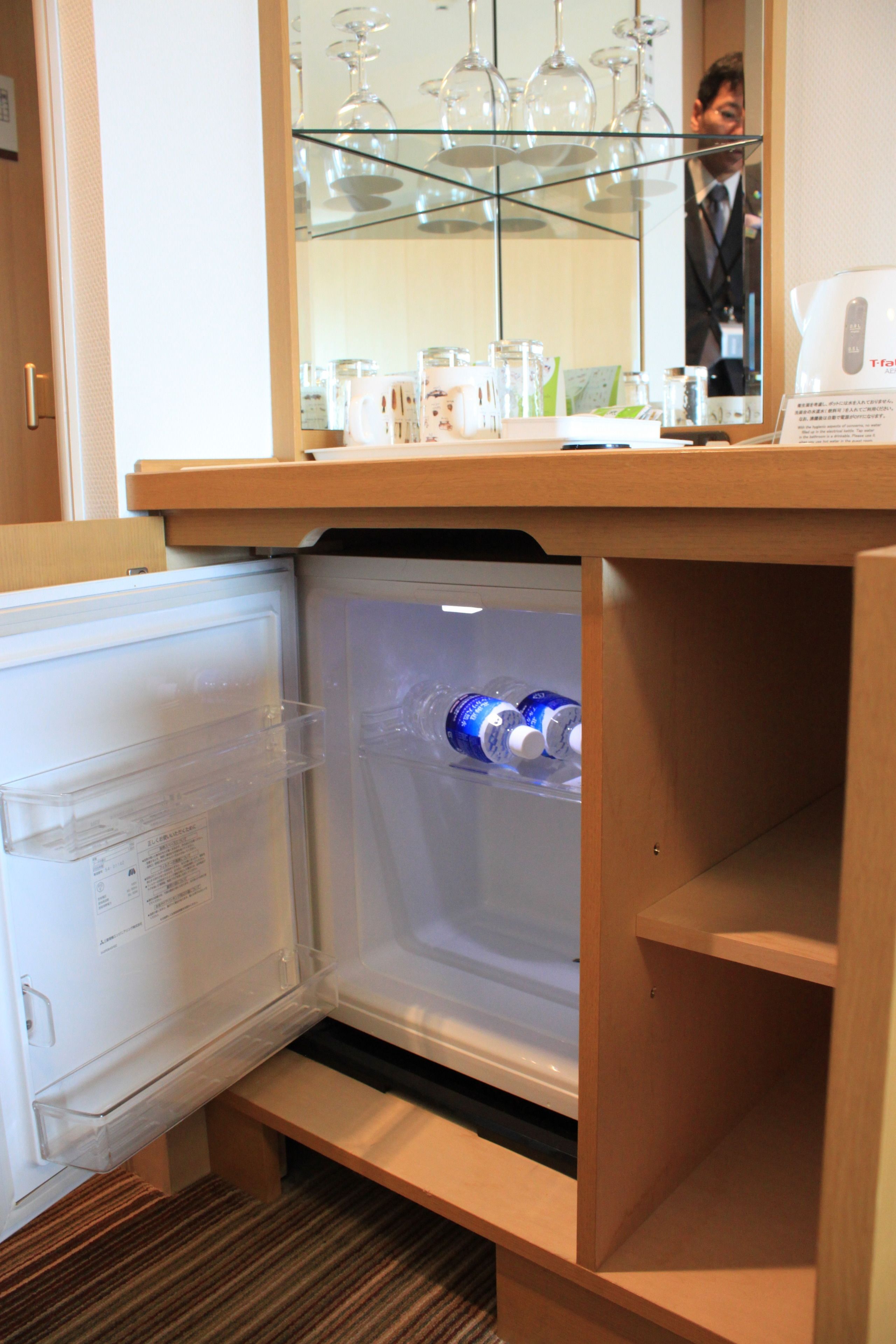 A compact refrigerator with a built-in wine glass holder and a water dispenser.