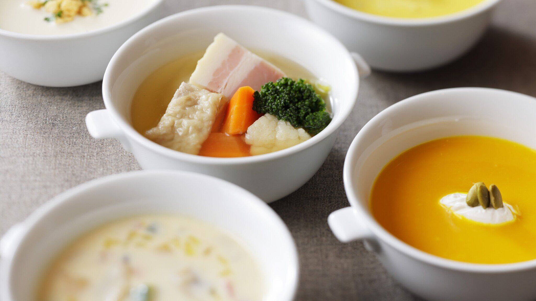 Four bowls of soup with different ingredients.