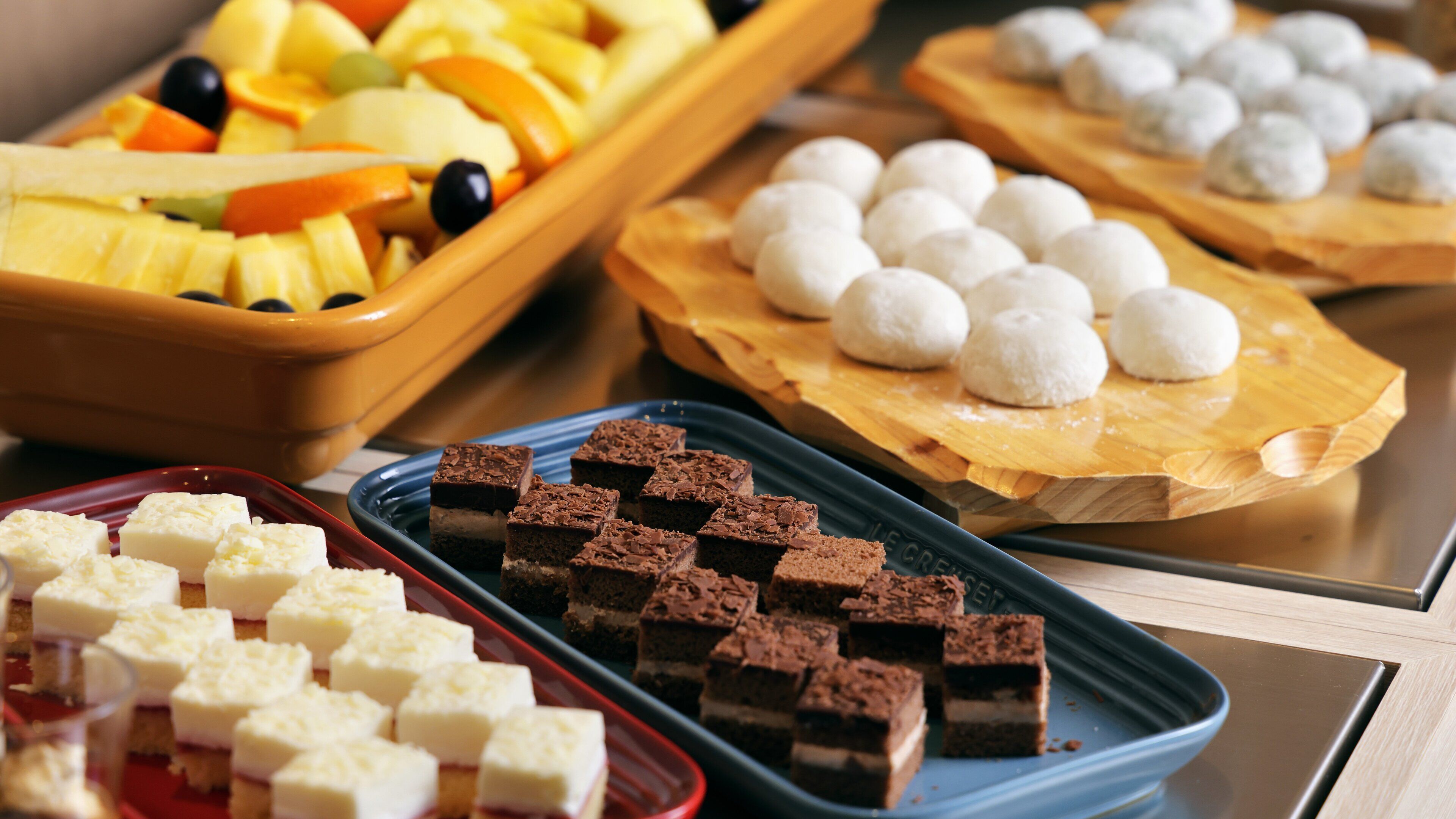A buffet with various desserts including brownies, white and chocolate squares, and round white balls.