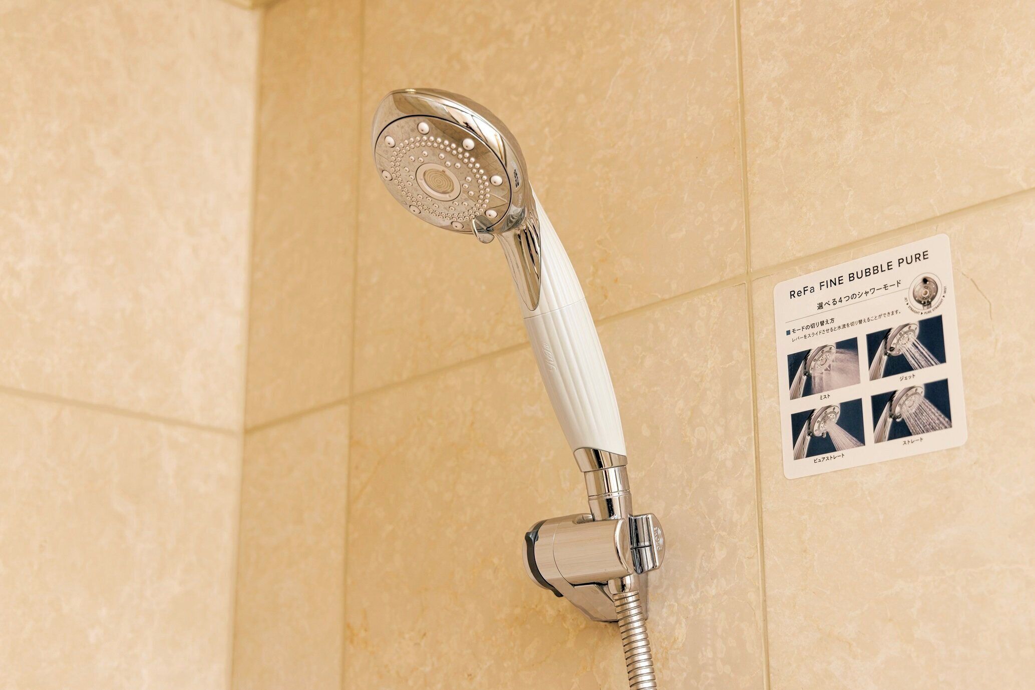 Una doccia con un manubrio bianco e un cartello che menziona ReFa Fine Bubble Pure.