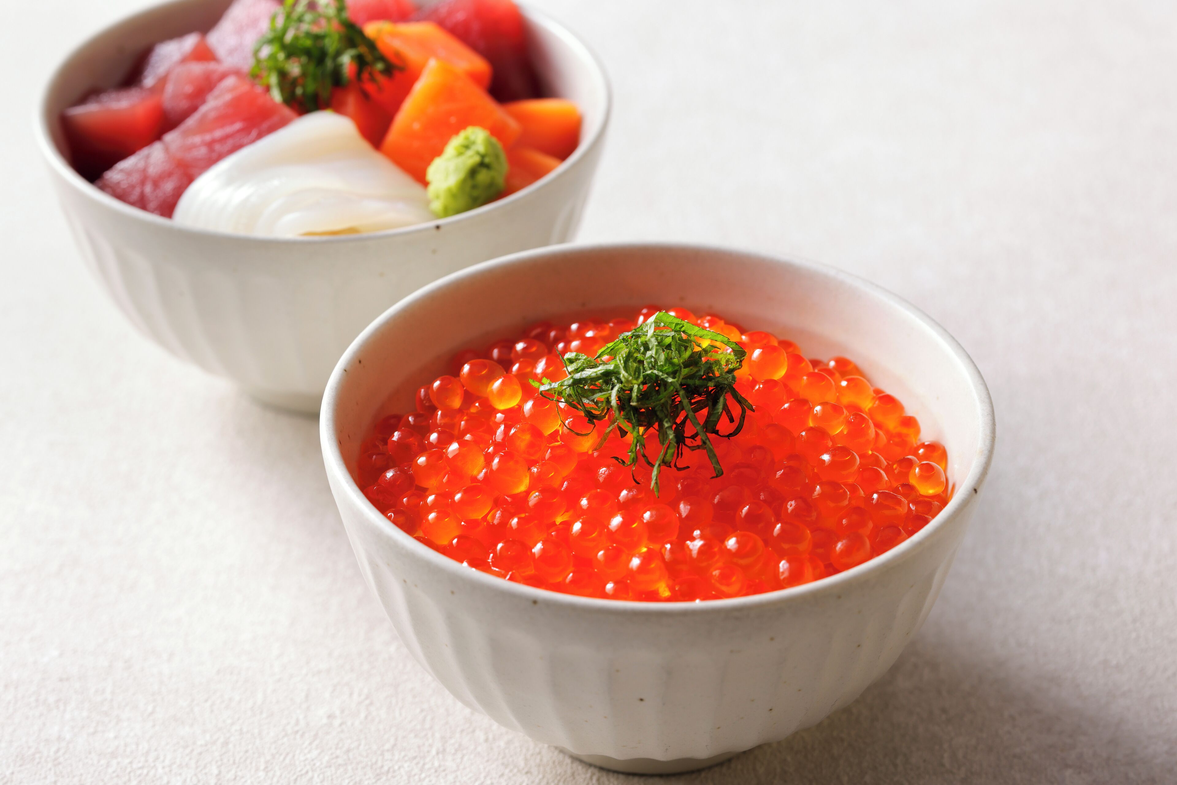 Deux bols de nourriture : l’un contient du caviar rouge et l’autre, de la pastèque et une cuillère de crème.