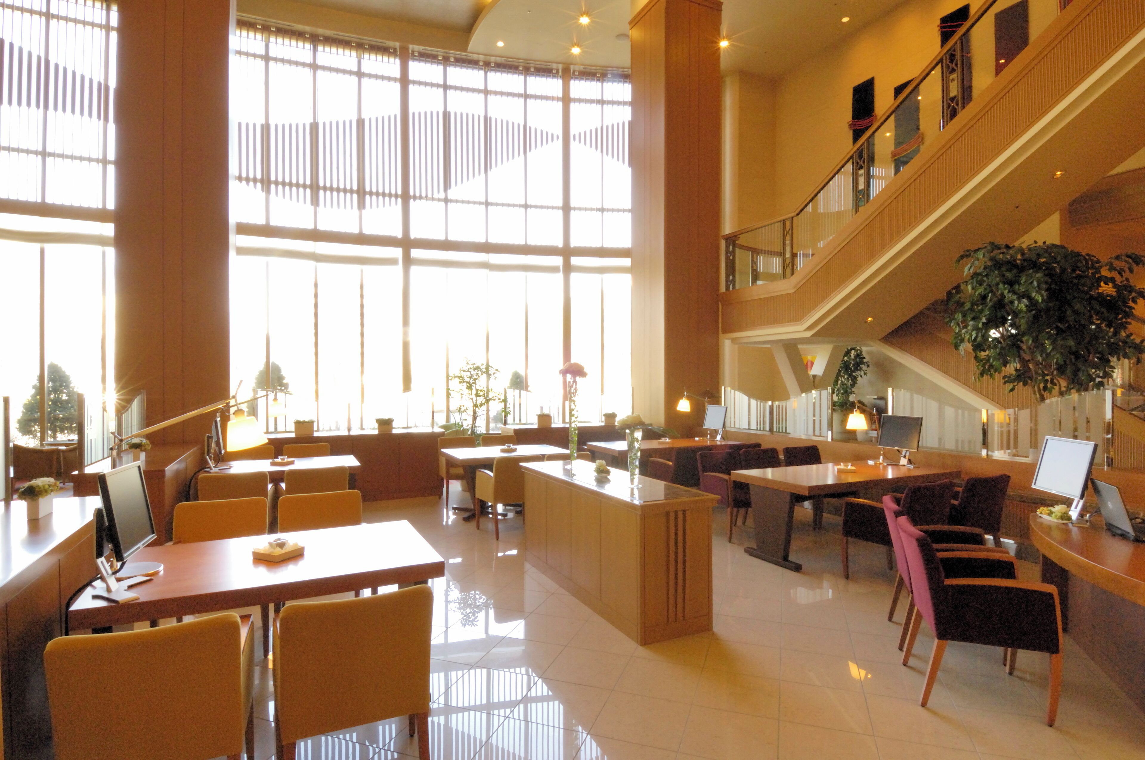 A spacious lobby with a central island, multiple seating areas, and a staircase leading to an upper level.