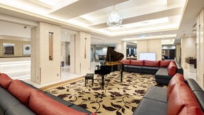 Un vaste espace de vie agrémenté d’un magnifique piano à queue, de canapés modernes et d’un lustre.