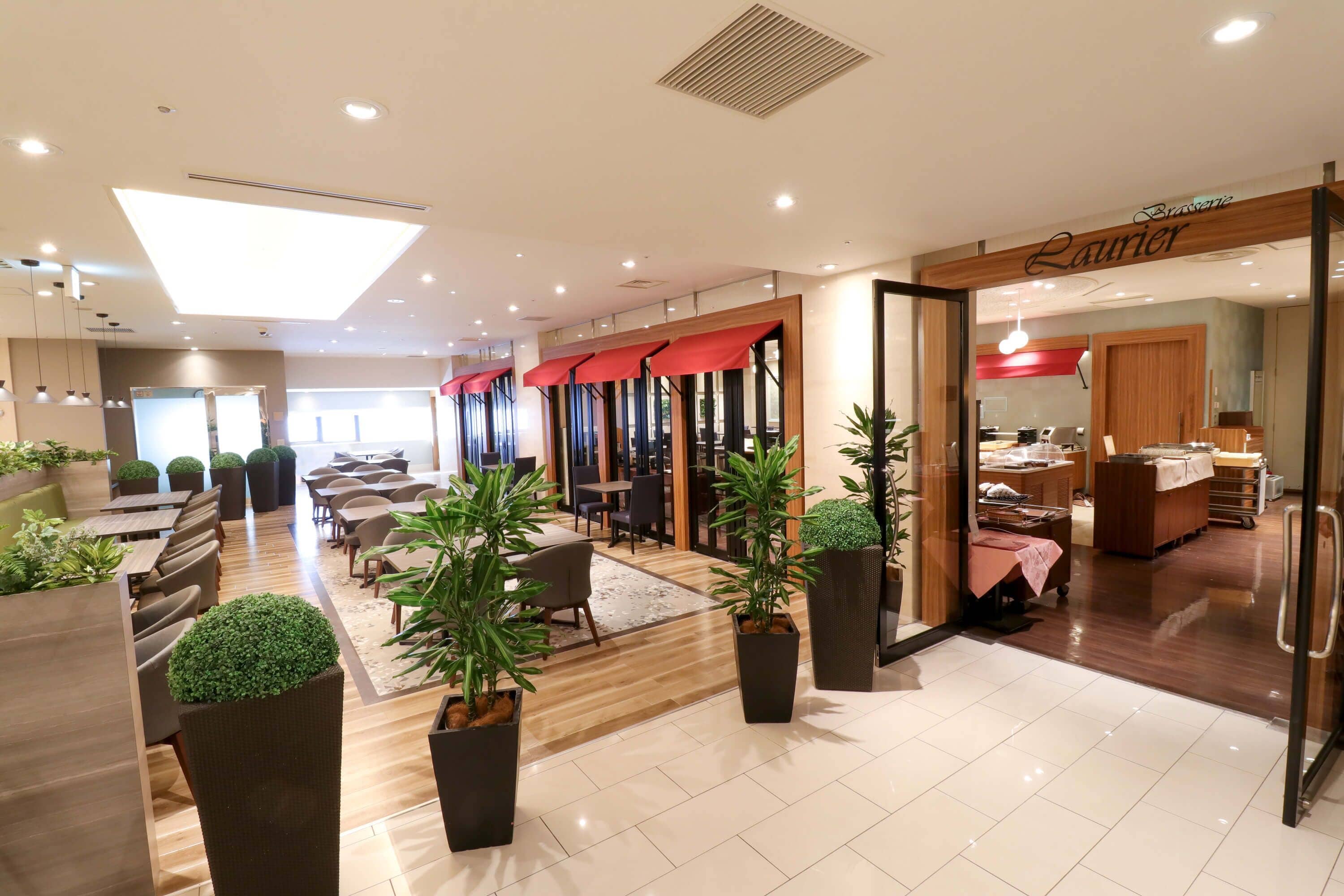 A modern hotel lobby with a reception area, seating arrangements, and a visible kitchen.