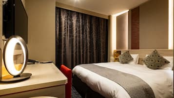 Una habitación de hotel con una cama, un escritorio con espejo y una silla roja.