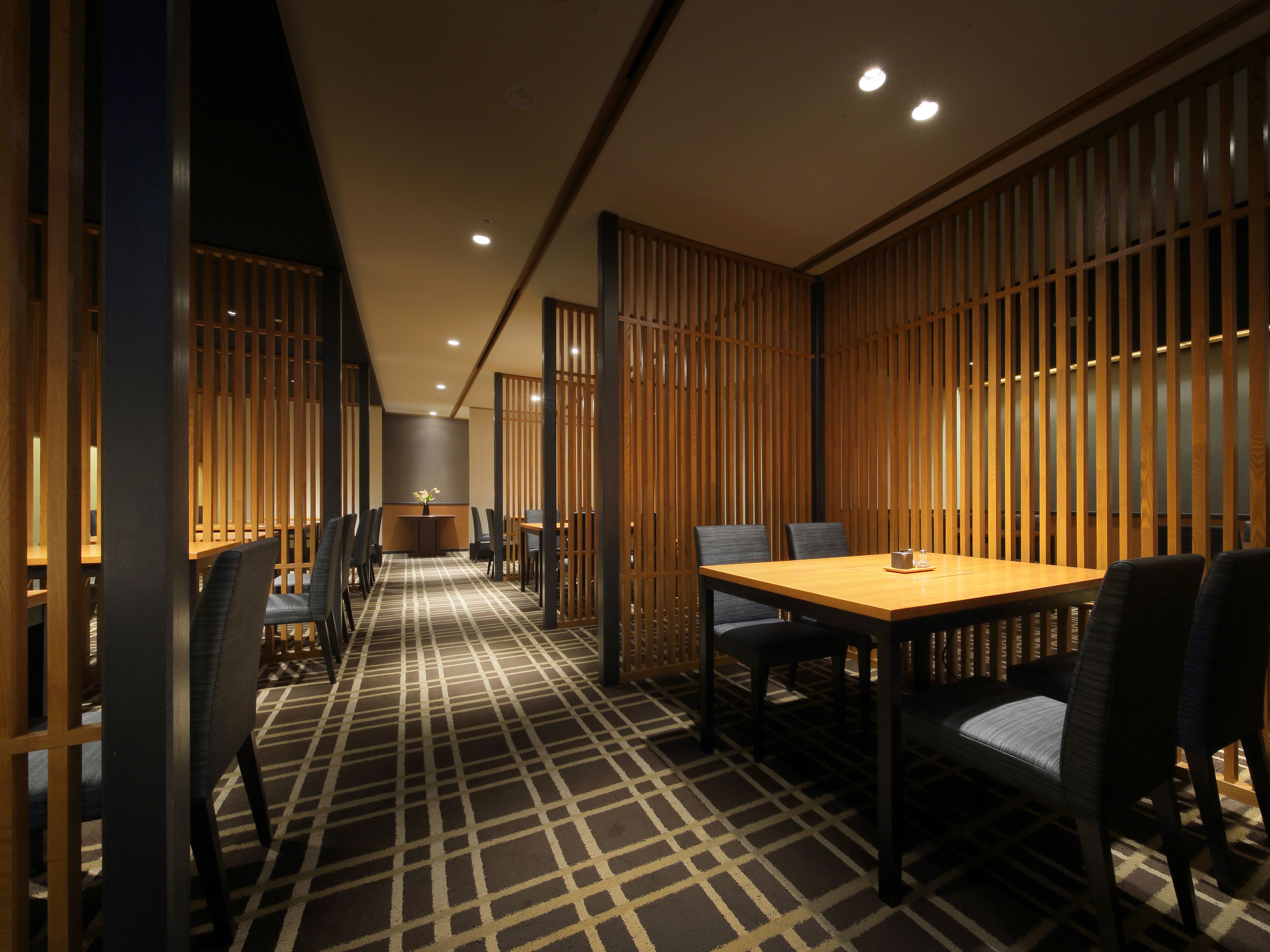 A modern dining area with a checkered floor, wooden partitions, and a central table with chairs.