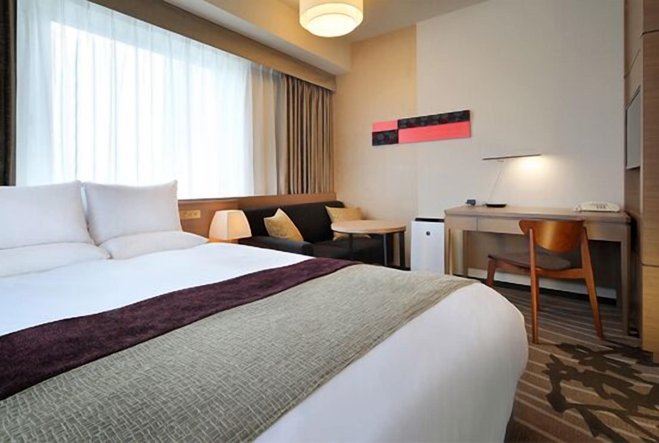A hotel room with a large bed, a desk, and a chair.