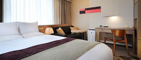 A hotel room with a large bed, a desk, and a chair.