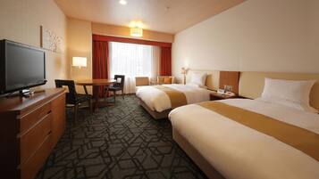 A hotel room with two beds, a desk with a television, a chair, and a lamp.