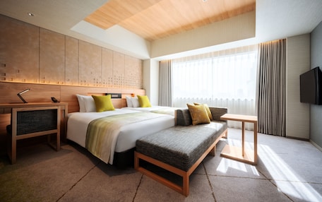 A modern hotel room with a large bed, bedside tables, a bench, and a TV.