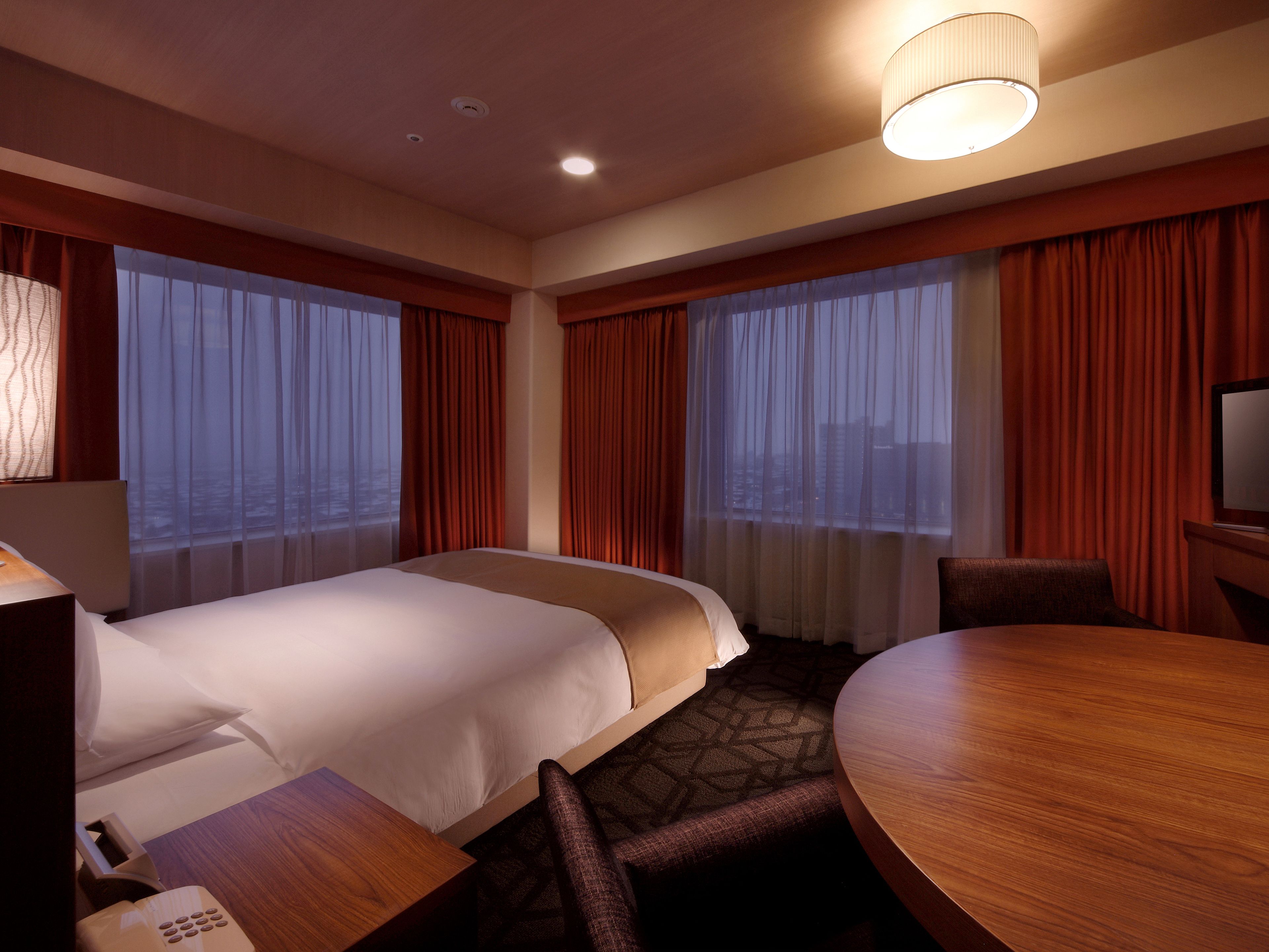 A hotel room with a large bed, a desk, a chair, and a television.