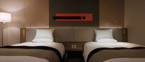 A hotel room with two beds, a nightstand, a lamp, and a wall-mounted control panel.