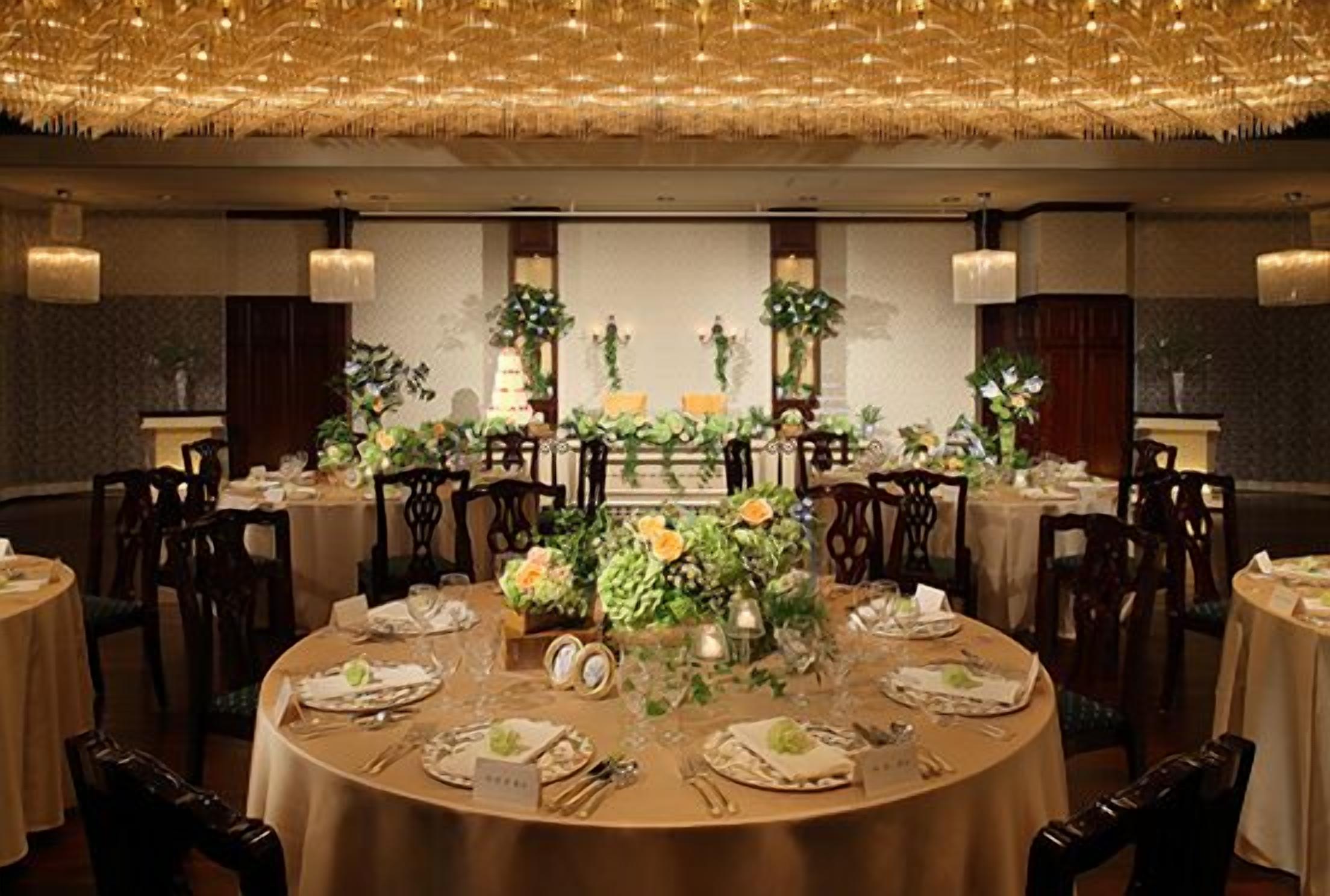 Uma sala de banquetes com mesas redondas preparadas para um evento formal, com centros de mesa florais e elegantes arranjos de mesa.