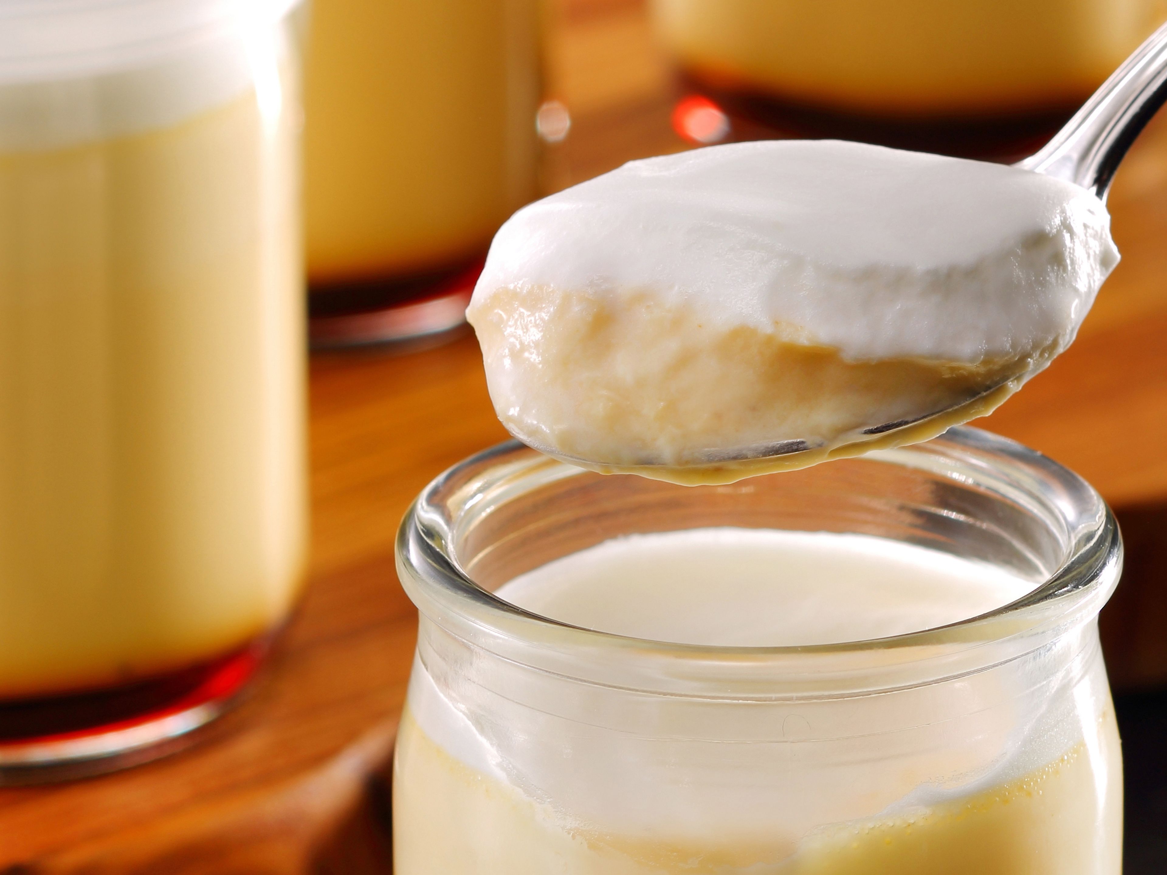 A spoonful of creamy dessert being lifted from a glass jar.