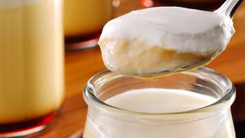A spoonful of creamy dessert being lifted from a glass jar.