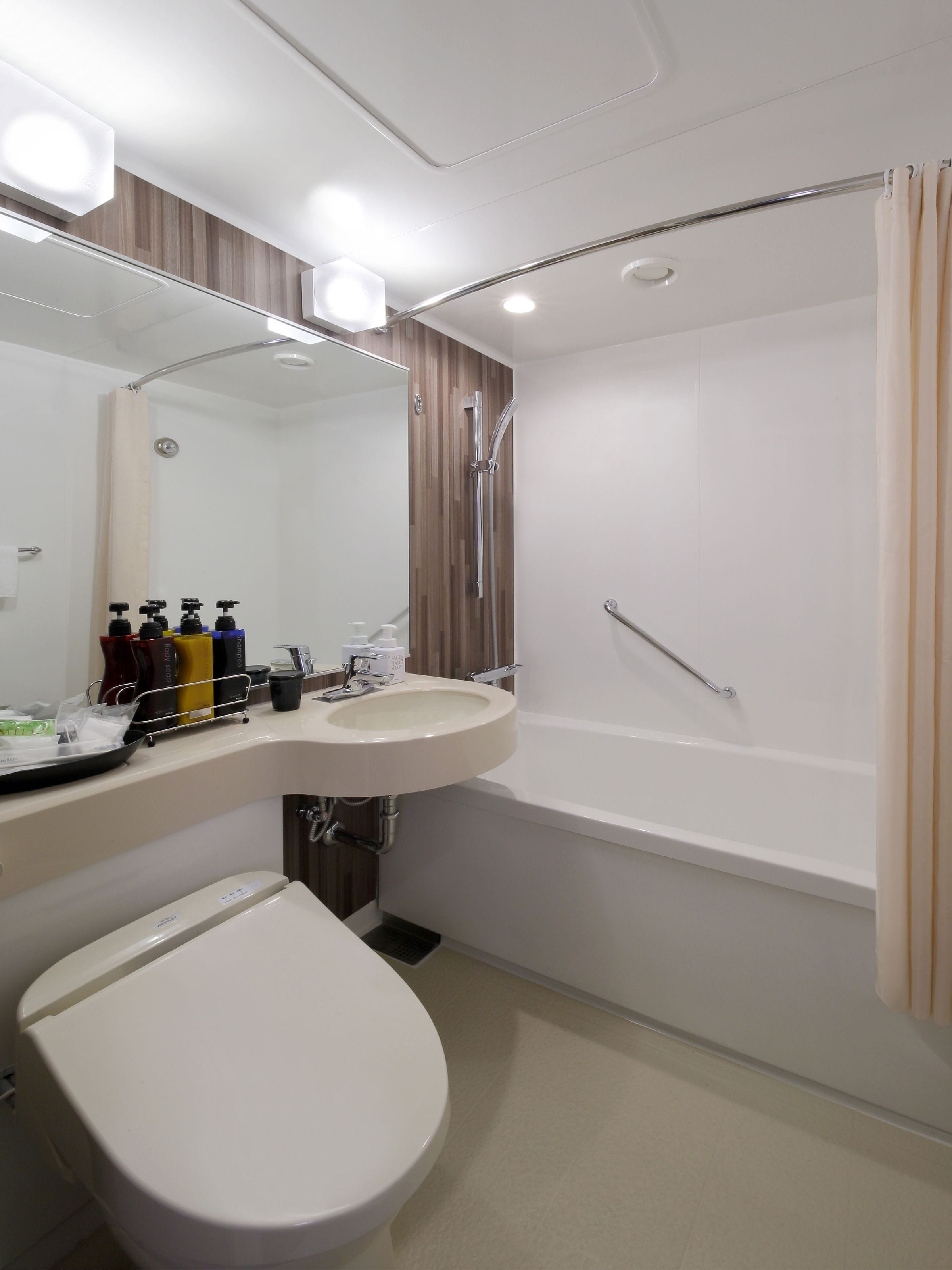 A modern bathroom with a white sink, mirror, and toilet.