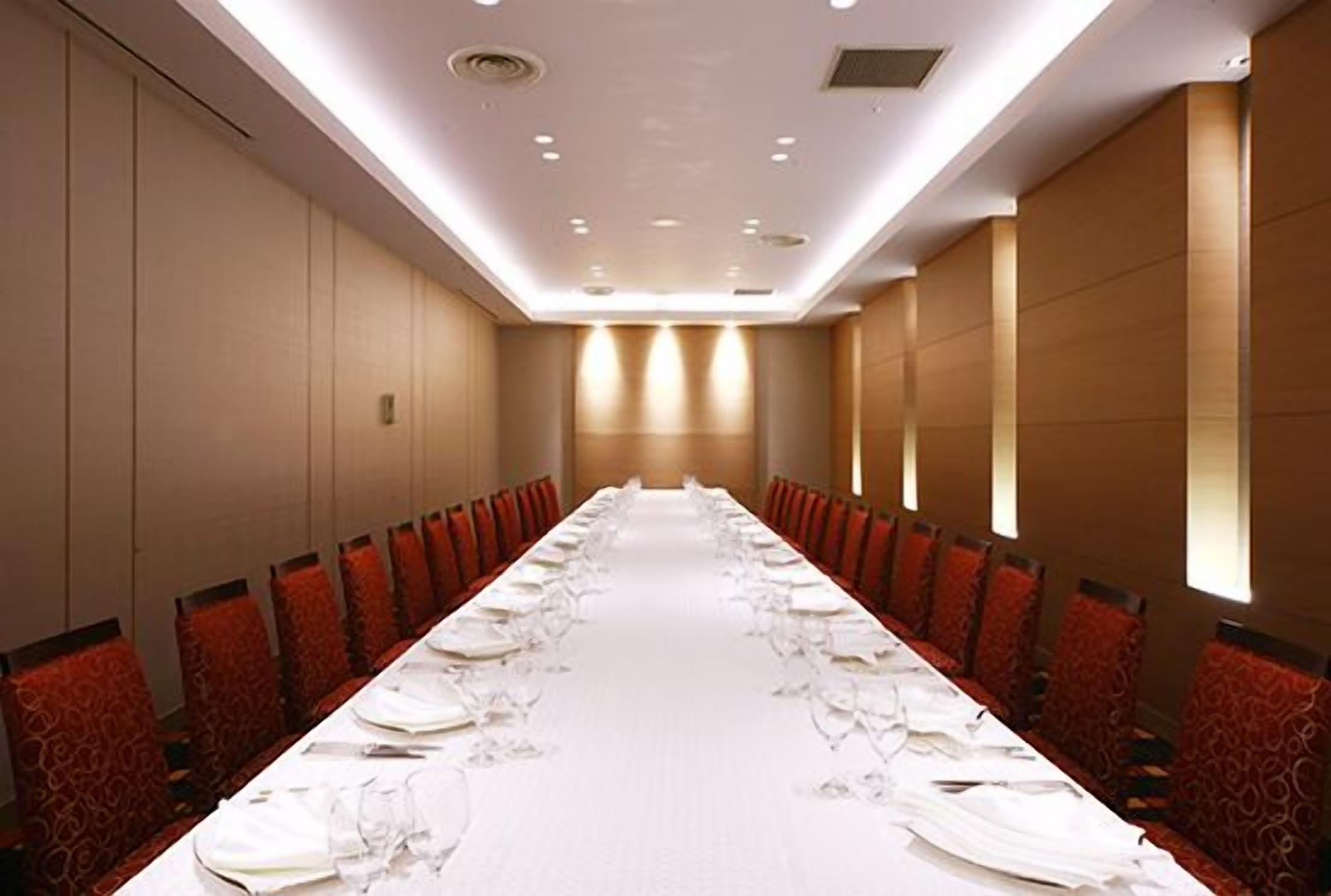 A conference room with a long table set for a meeting, equipped with chairs and tables.
