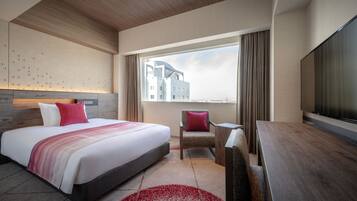 A modern hotel room with a large bed, a desk, and a TV.
