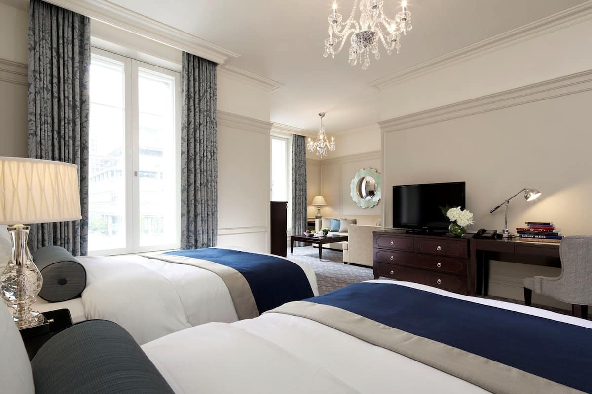 Habitación de hotel con dos camas, un escritorio, un televisor y un candelabro.