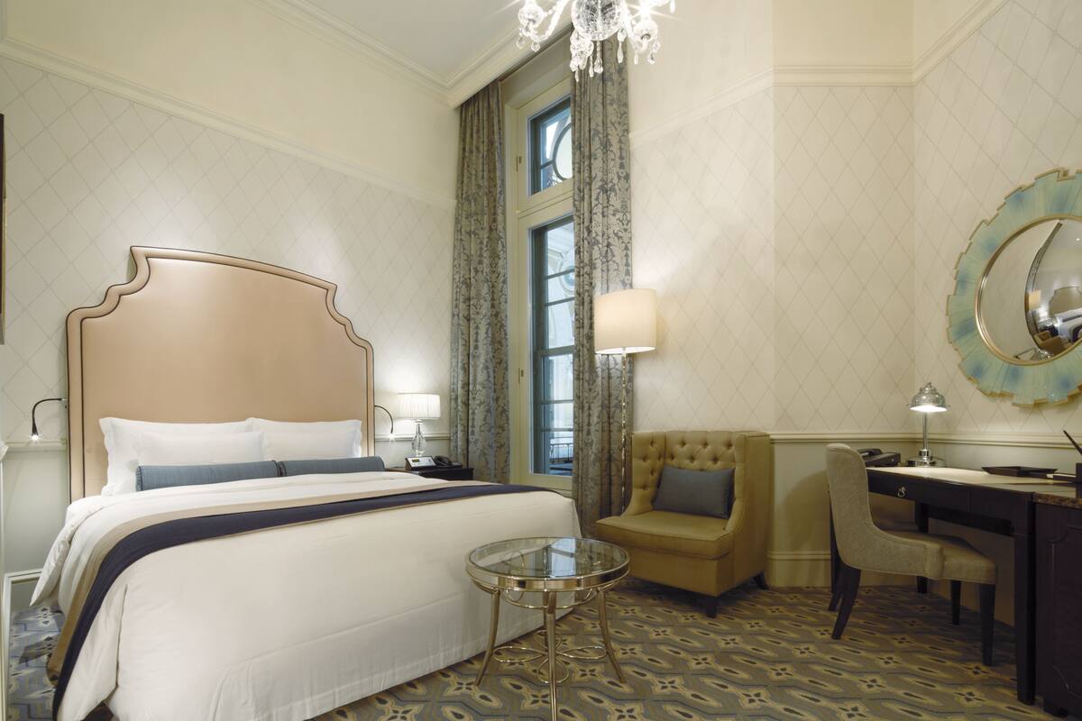 Una habitación de hotel con una cama grande, un escritorio, una silla y una mesita.