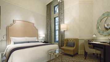 A hotel room with a large bed, a desk, a chair, and a small table.