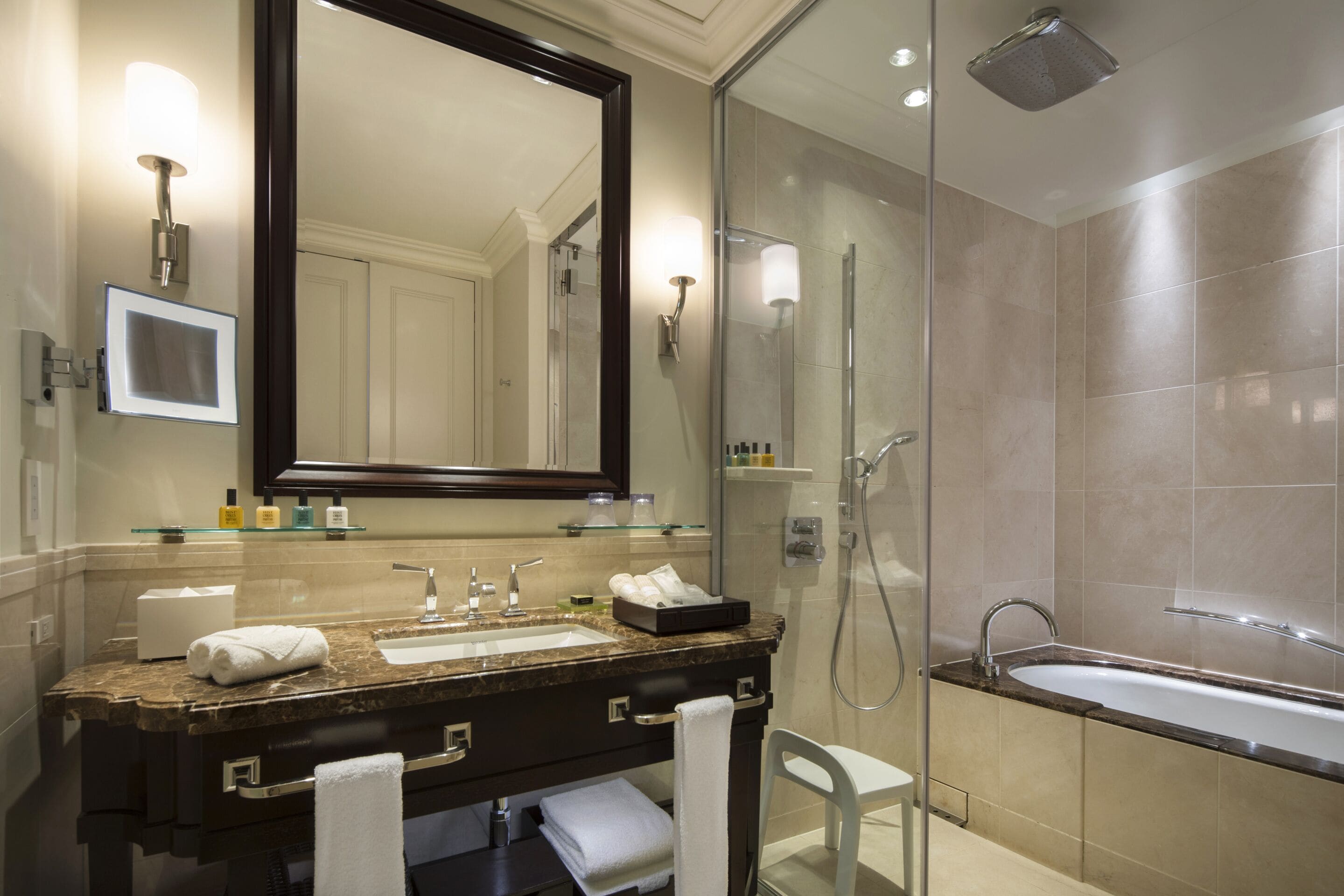 A modern bathroom with a large mirror, a sink, a shower, and a bathtub.
