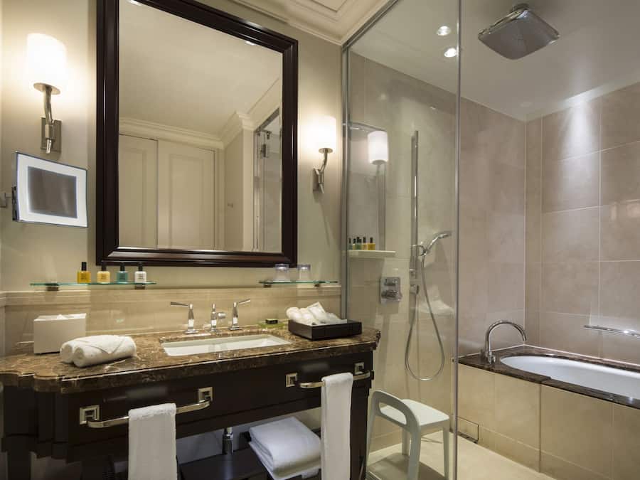 A modern bathroom with a large mirror, a sink, a shower, and a bathtub.