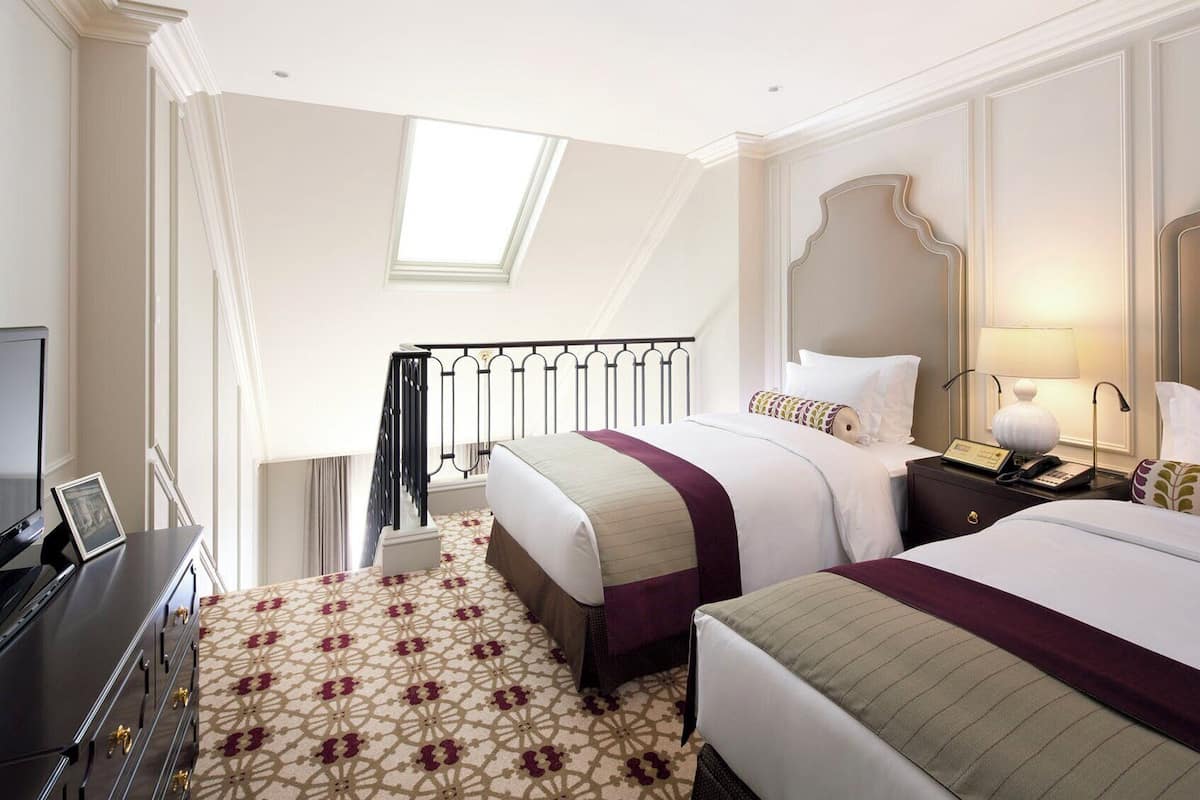 Habitación de hotel con dos camas, un escritorio con computadora, una lámpara de escritorio y un teléfono.