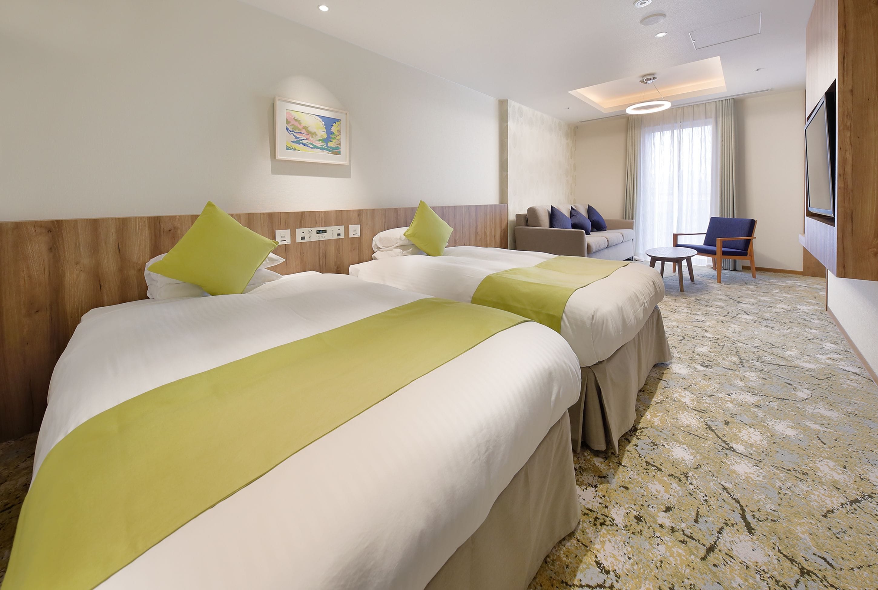 A hotel room with two beds, a sofa, a TV, and a large window.