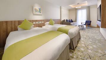 A hotel room with two beds, a sofa, a TV, and a large window.