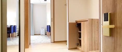 Una habitación de hotel moderna con suelo de madera, un escritorio pequeño y una silla. Hay una puerta corredera que da a otra habitación.