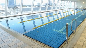 Una piscina interior con baldosas azules cristalinas, separadores de carril amarillo y barandillas de metal.