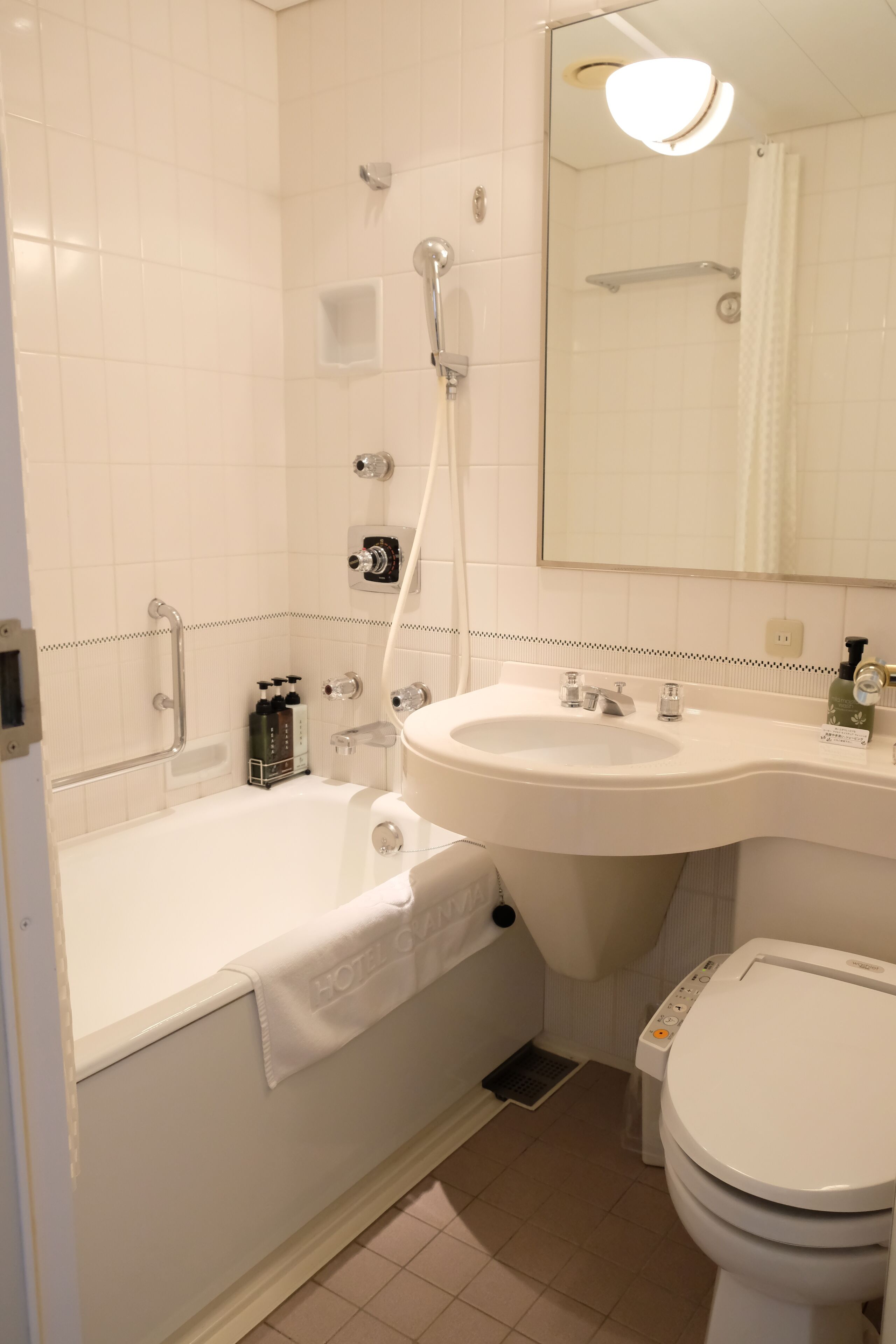 A hotel bathroom with a bathtub, sink, toilet, and a shower.