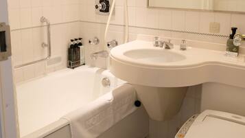 A hotel bathroom with a bathtub, sink, toilet, and a shower.
