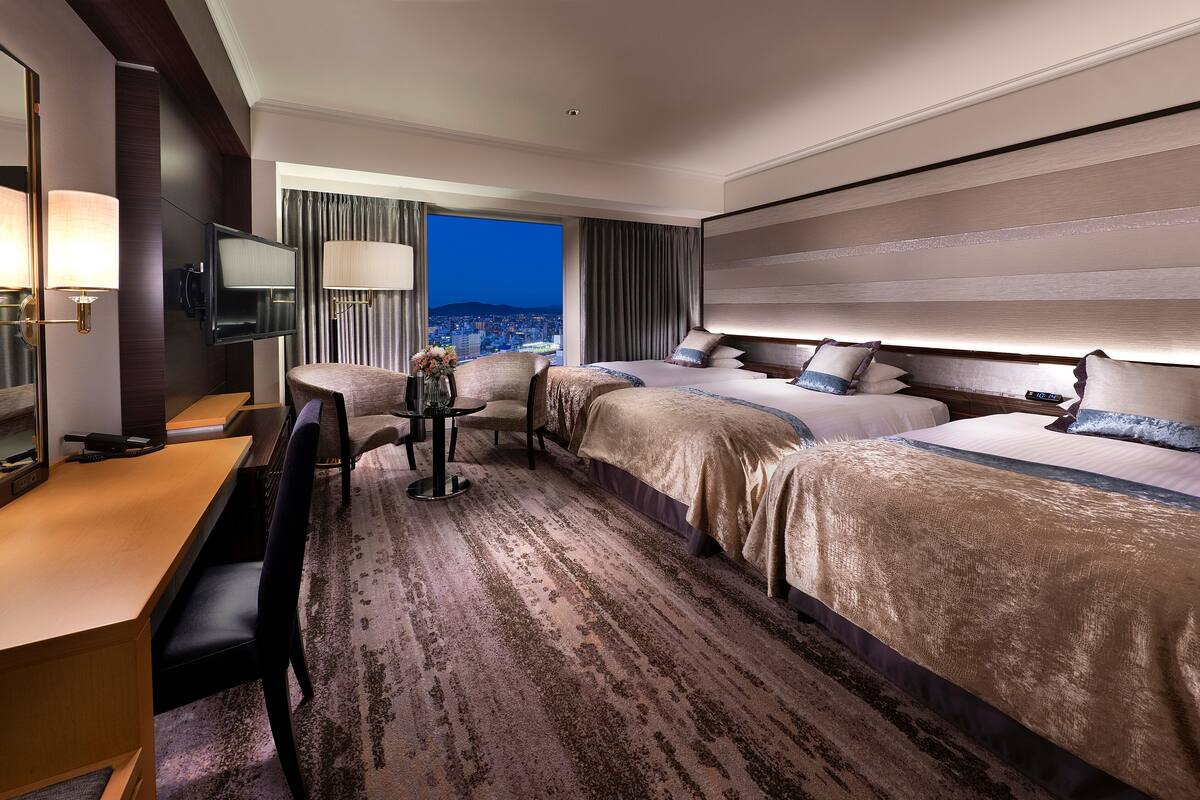A hotel room with a large bed, a desk, a chair, and a TV.