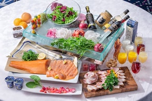 Una mesa con diversos alimentos, como salmón, carne y verduras, además de bebidas y salsas.