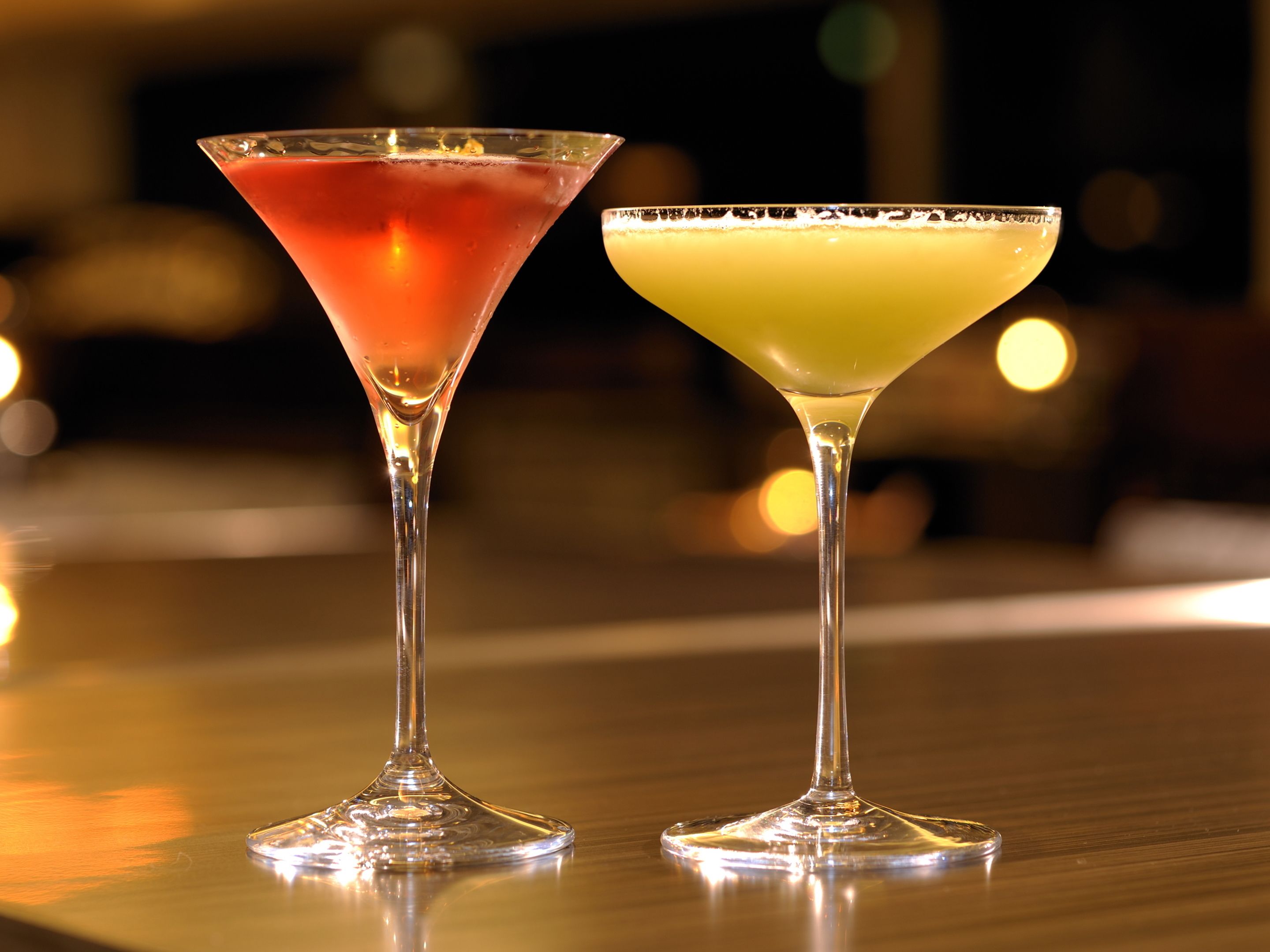 Duas taças de martini sobre uma superfície refletora.