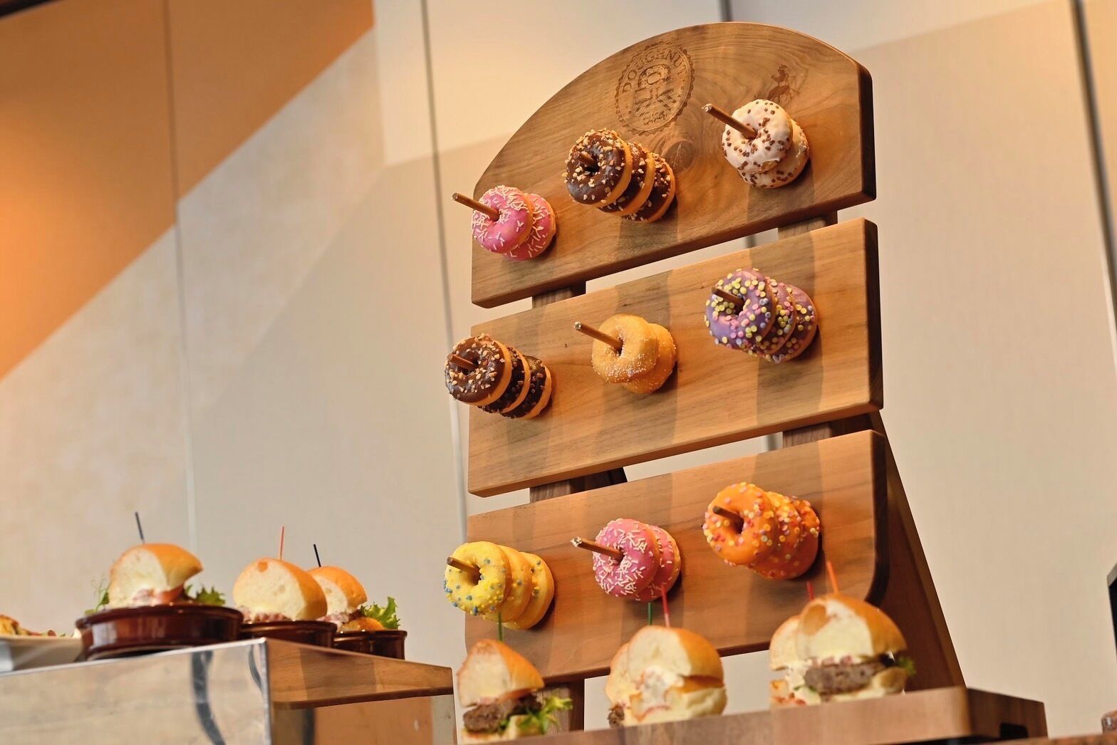 Un expositor de madera con varios donuts y sándwiches.