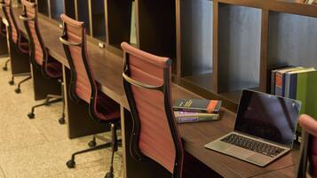 A row of office chairs with a laptop and books on a desk.