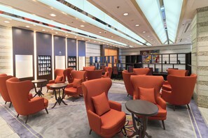 A lobby with orange seating, a reception desk, and a wall with framed pictures. - Hotel Granvia Wakayama (Wakayama)