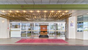 L’entrée d’un hôtel, avec un tapis rouge, des portes en verre et un auvent vert illuminé.