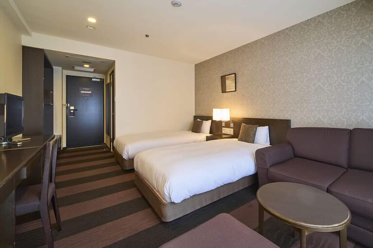 Een hotelkamer met twee bedden, een bank, een tafeltje en een televisie.