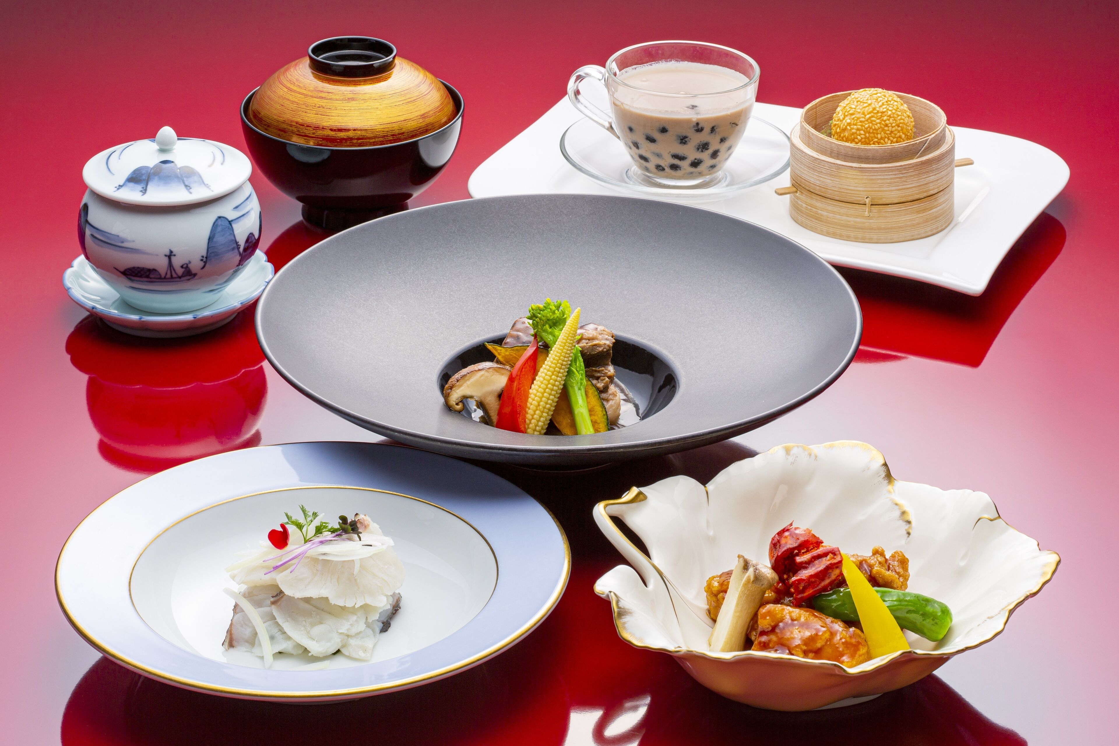 A table set with various dishes, including a bowl of vegetables, a plate of fish, and a cup of tea.