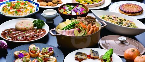 A variety of dishes and food items on a table, including pastries, salads, and a pot of food.