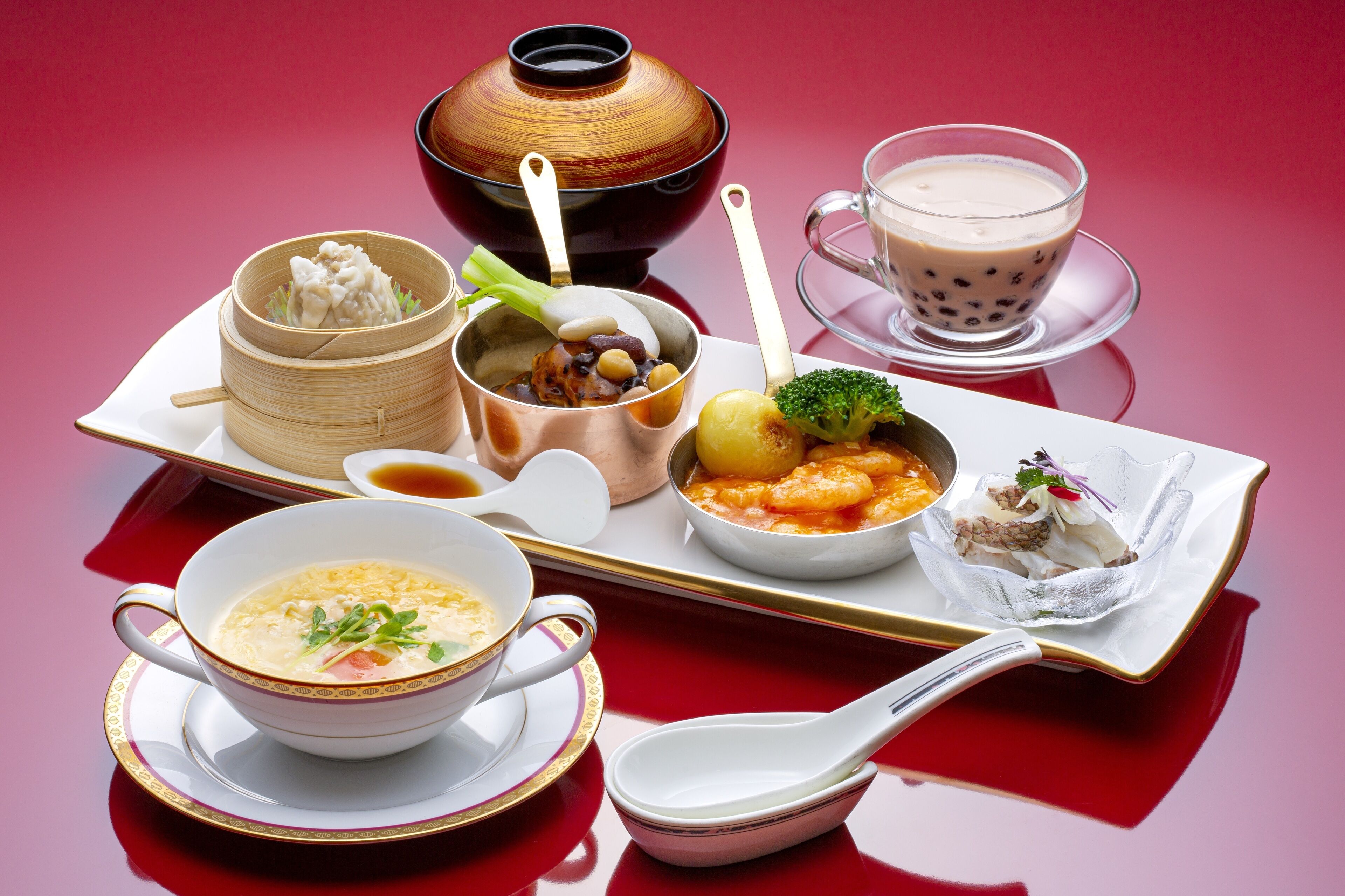 A variety of dishes including soup, dumplings, and a dessert on a tray.